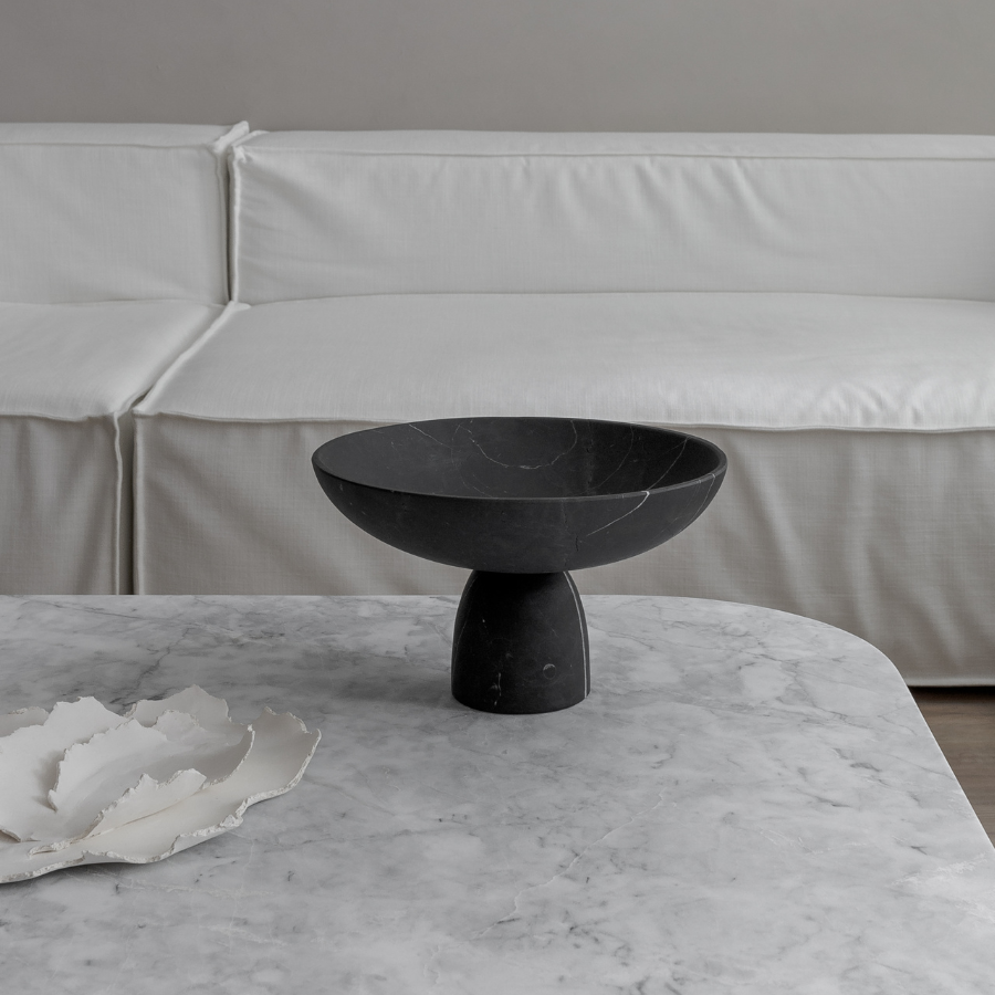 black marble sculptural bowl on white marble coffee table in white livingroom