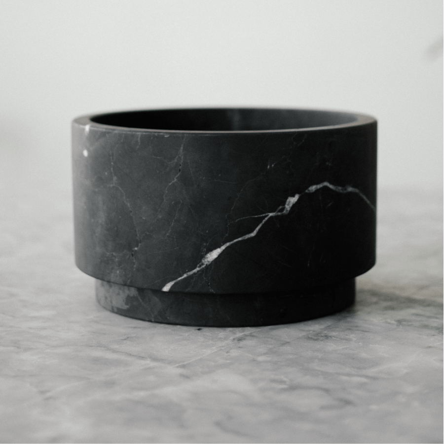 black marble low footed bowl on a marble table top