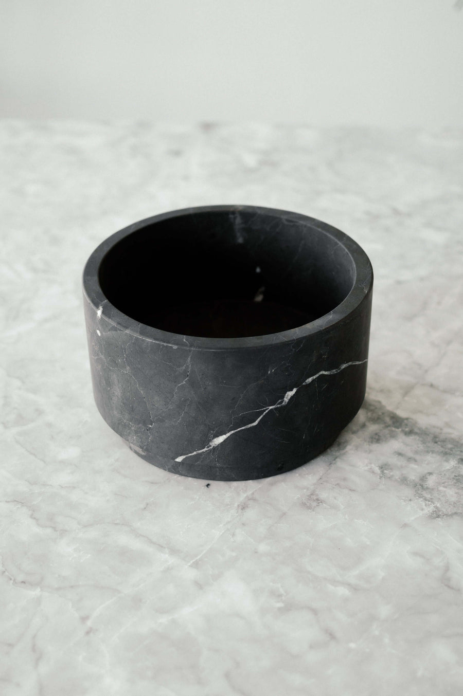 black marble low footed bowl on a marble table top