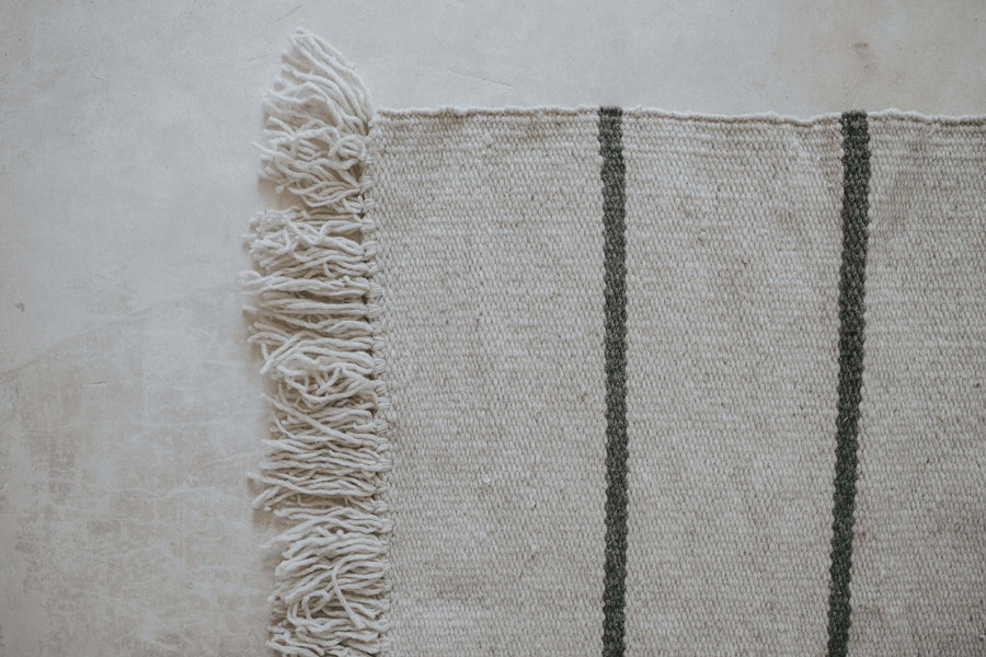 handmade wool beige striped rug on a stone floor 