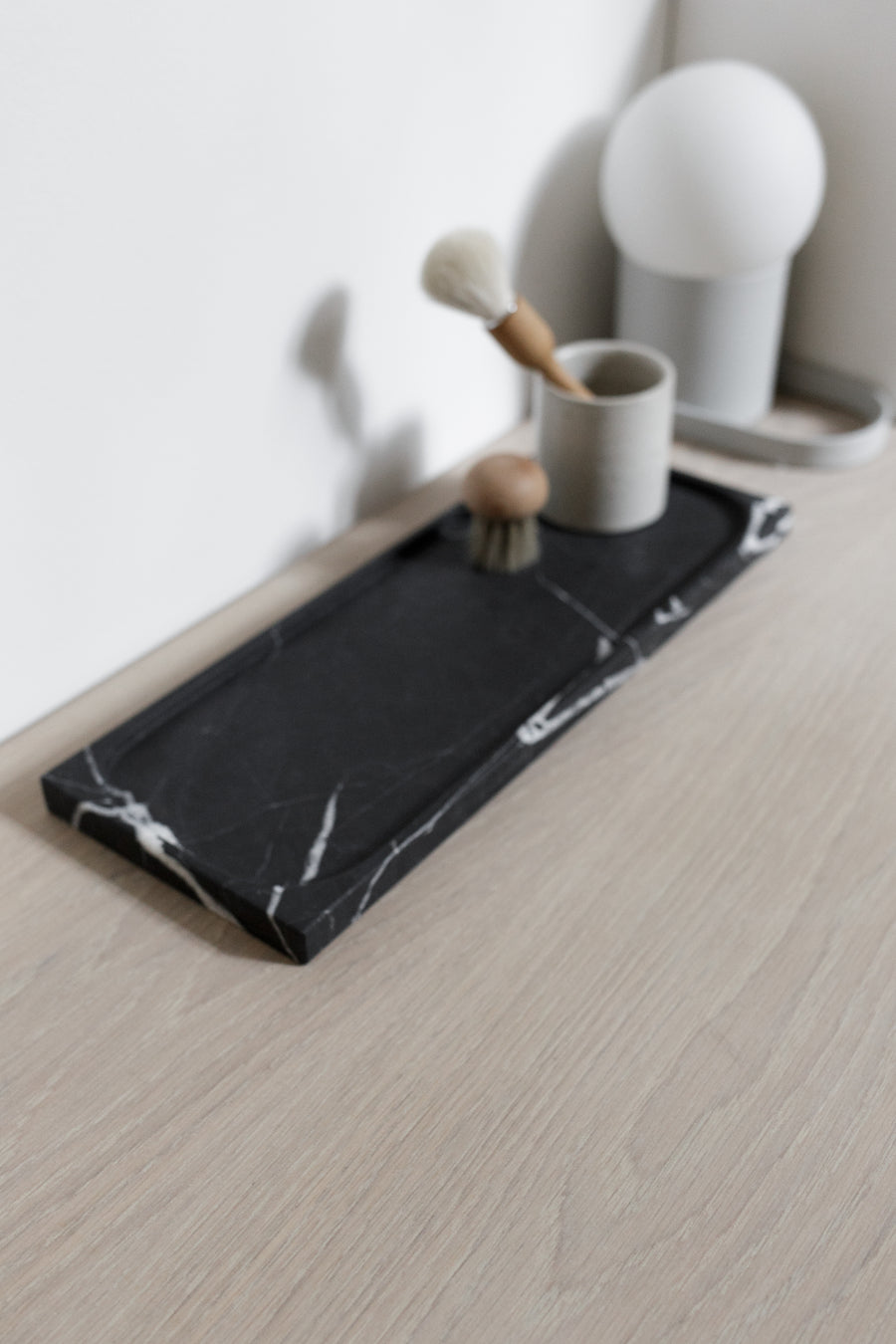 closeup of black marble rectangular tray with beauty tools on top 