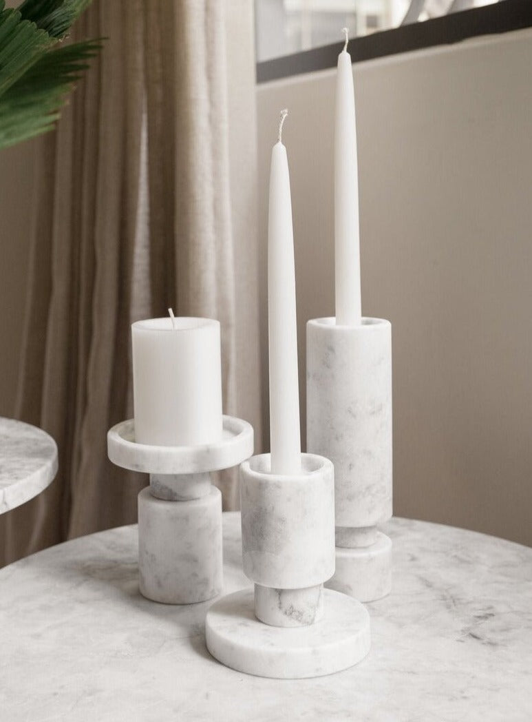 set of three white marble candle holders on a white marble table